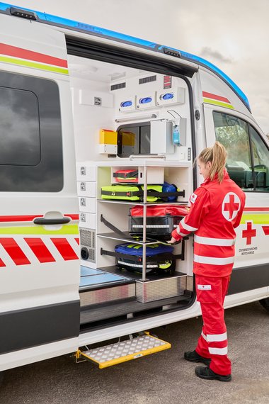 Eine Sanitäterin, verlädt einen Notfallrucksack in das neue Großraumfahrzeug dabei ist ihr Arbeitsplatz sehr ergonomisch.