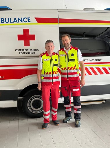 Zwei Rettungssanitäter stehen vor einem Rettungswagen, links Hubert Leitinger, recht Stefan Herbst