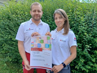 Rotkreuz-Mitarbeiter mit Veranstaltungsplakat für das Betreute Reisen