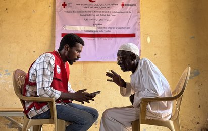 Ein Mitarbeiter des Roten Kreuzes im Gespräch mit einem Mann