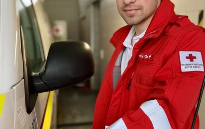 © Credit: OÖRK / Viktoria Lindner Michael steht beim Rettungsauto und bereitet es vor für die nächste Ausfahrt.