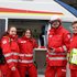 4 Rotkreuz-Sanitäter und Sanitäterinnen vor Rettungswagen
