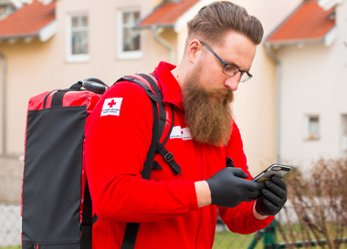 Ein First Responder ist unterwegs zum Notfall. Am Rücken trägt er einen Notfallrucksack, in der Hand hält er ein Handy, mit dem er alarmiert wurde.