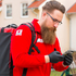 Ein First Responder ist unterwegs zum Notfall. Am Rücken trägt er einen Notfallrucksack, in der Hand hält er ein Handy, mit dem er alarmiert wurde.