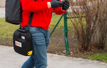 Ein First Responder ist unterwegs zum Notfall. Am Rücken trägt er einen Notfallrucksack, in der Hand hält er ein Handy, mit dem er alarmiert wurde.