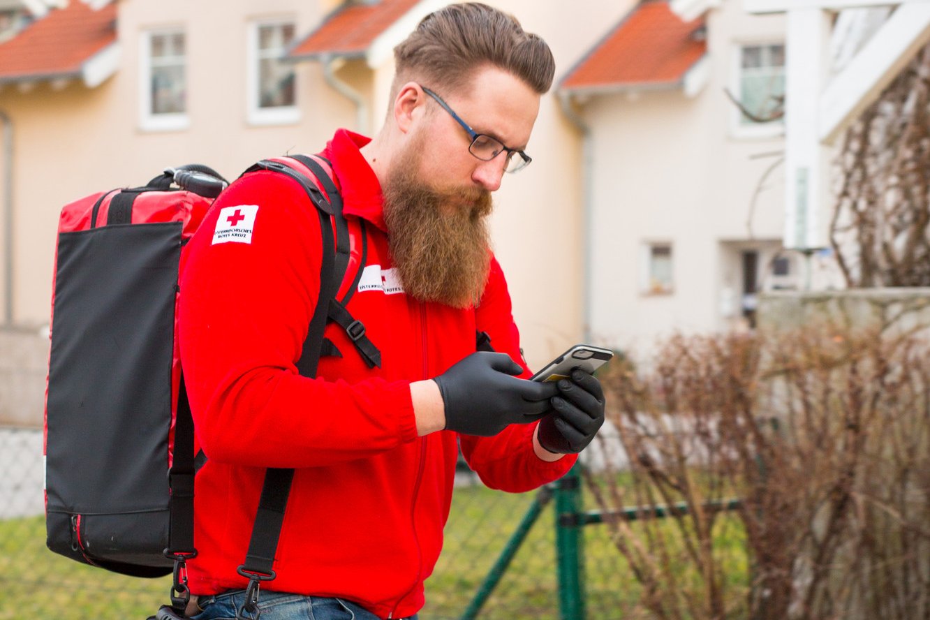 © ÖRK/Thomas Holly Kellner Ein First Responder ist unterwegs zum Notfall. Am Rücken trägt er einen Notfallrucksack, in der Hand hält er ein Handy, mit dem er alarmiert wurde.