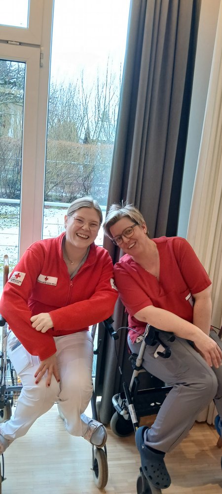 Zwei Mitarbeiter:innen posieren und lächeln in die Kamera