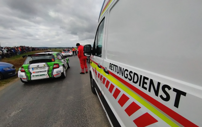 Ein Rettungstransportwagen steht neben einem Rennauto abfahr- und einsatzbereit bei der Herbstrallye in Waidhofen/Thaya.