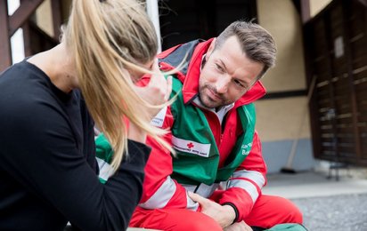Rotkreuz-Mitarbeiter des Kriseninterventionsteams im Gespräch mit betroffener Person.