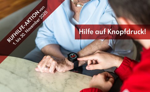 Ein Sanitäter zeigt mit seiner Hand auf die Rufhilfe-Uhr am Arm einer älteren Dame, auf der "SOS" zu lesen steht