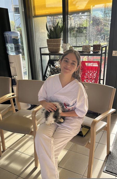 Eine Mitarbeiterin des Seniorenwohnhauses sitzt und hält ein Tier auf ihrem Schoß.