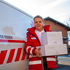 Eine Zuhause-Essen-Mitarbeiterin steht mit Essenspaketen vor einem Rotkreuz-Auto