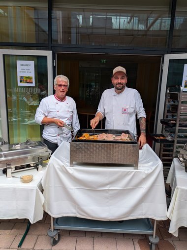 Zwei Köche, die am Griller stehen und Essen zubereiten