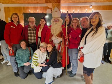 Gruppenfoto von Mitarbeiterinnen des Roten Kreuzes sowie Unterstützerinnen des Vereins "Seekirchen hilft" mit dem Nikolaus