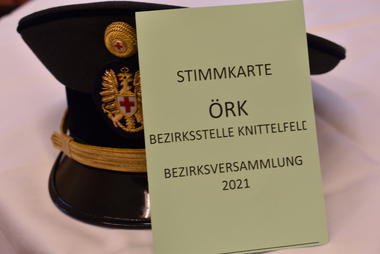 Rotkreuz-Tellerkappe mit Stimmzettel für die Knittelfelder Bezirksversammlung 2021 davor.