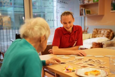 Eine Pflegekraft spielt Memory mit einer Seniorenwohnhaus-Bewohnerin
