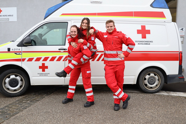 Drei Rettungssanitäter vor einem Rettungswagen
