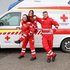 Drei Rettungssanitäter vor einem Rettungswagen