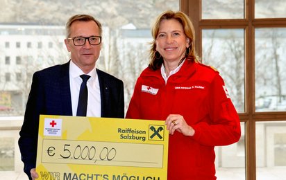 Heinz Konrad, links, Generaldirektor Raiffeisenverband Salzburg, bei der Spendenübergabe an Sabine Tischler, Landesgeschäftsführerin RK Salzburg. Sie halten gemeinsam einen großen Scheck mit der Spendensumme in der Hand.