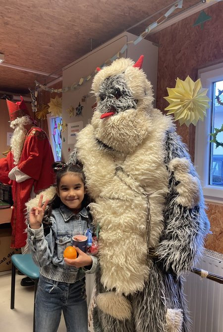 Der Krampus gemeinsam mit einem Kind aus dem Flussbauhof, im Hintergrund der Nikolaus.