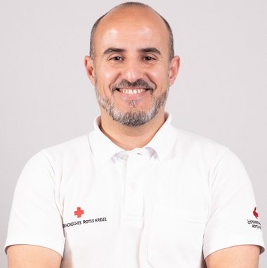 Elvis Peristeri im Portrait und mit Rotkreuz-Polo