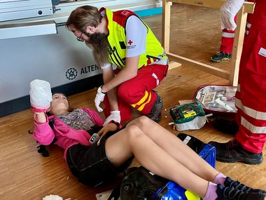 Ein Sanitäter versorgt eine am Rücken liegende Patientin
