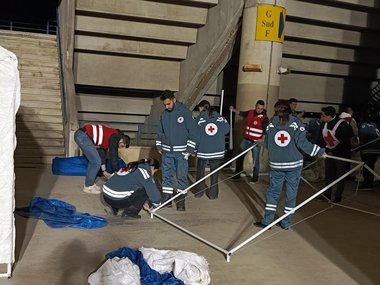 Jugendliche Freiwillige des LRC helfen bei der Errichtung von Zelten in der Notunterkunft "Sport City".