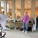 Die Hausleitung und eine Mitarbeiterin des Seniorenwohnhauses Obertrum präsentieren den Flohmarkttisch, der mit diversen Materialien und Gegenständen gefüllt ist.