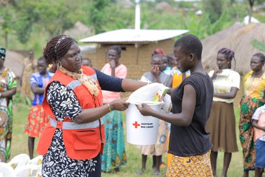 Rotkreuzhelferin in Uganda übergibt Benefizientin ein Menstrual Hygiene Kit