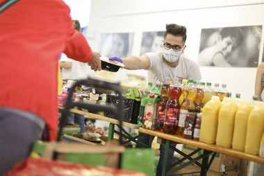 ein Mitarbeiter der Tafel der Lebensmittel an Bedürftige vergibt
