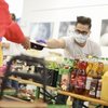 ein Mitarbeiter der Tafel der Lebensmittel an Bedürftige vergibt