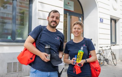Eine Mitarbeiterin und ein Mitarbeiter der Wohnungslosenhilfe des Wiener Roten Kreuzes mit Hitzeschutzpaketen