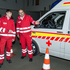 Gerald Muhr - Bezirksausbildungsleiter für Sichere Einsatzfahrer - weist einen jungen Mitarbeiter in Ausbildung in das richtige Einparken eines Rettungswagens ein. Beide tragen Rotkreuz-Einsatzuniform und stehen vor einem Rettungswagen.