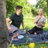 Ein Mann und eine Frau sitzen auf einer Picknickdecke. Sie greift sich nach einem Wespenstich an den Hals.