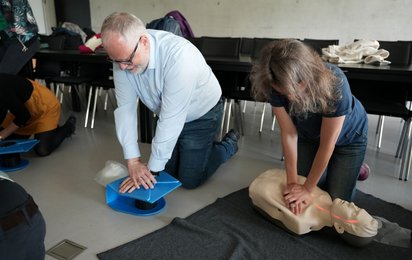 Zwei Mitarbeiterinnen der Universität Salzburg üben an Trainingspuppen die Herzmassage.