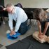 Zwei Mitarbeiterinnen der Universität Salzburg üben an Trainingspuppen die Herzmassage.