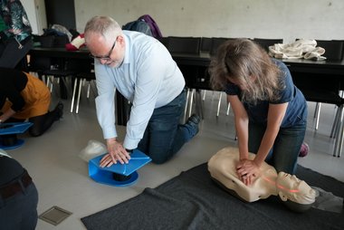 Zwei Mitarbeiterinnen der Universität Salzburg üben an Trainingspuppen die Herzmassage.