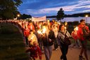 Rotkreuzler:innen gehen im Fackelzug an der Donaulände entlang.