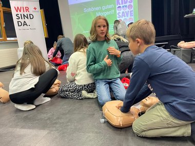 Mehrere Schüler knien am Boden und üben an Rettungspuppen die Herzmassage.