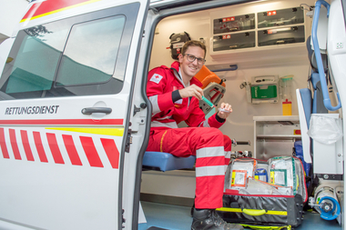 Marian Cernko - Notfallsanitäter - sitzt in einem Rettungswagen und zieht gerade ein Medikament aus einer Ampulle mit einer Spritze auf.