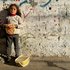 Mädchen in Gaza steht an einer Wand und hält ein Brot in der Hand