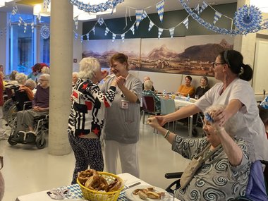 Eine Pflegeperson tanz mit einer Bewohnerin, während eine zweite Pflegeperson mit einer anderen Bewohnerin mit den Händen winkt.
