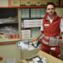 Freddy Lechner steht in Rotkreuz-Uniform in einem Lager voller Sanitätsmaterialien.