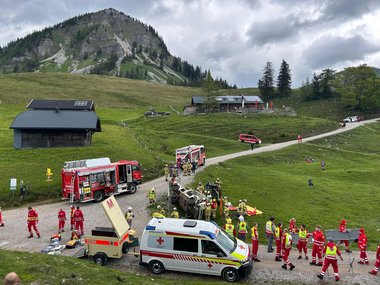 Blick auf Genneralm. Im Vordergrund ein Rettungswagen mit Anhänger, dahinter ein umgekipptes Fahrzeug und Einsatzkräfte.