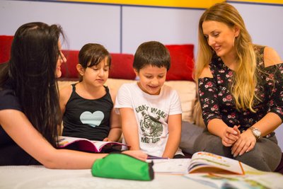 Zwei Rotkreuz-Freiwillige helfen Kindern beim Lernen