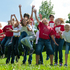 Kindergruppe springt auf einer Wiese.