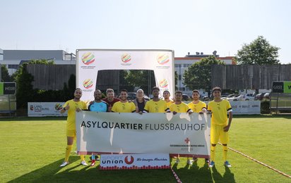 Das Fußballteam des Rotkreuz-Asylquartiers Flussbauhof lächelt in die Kamera.