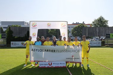 Das Fußballteam des Rotkreuz-Asylquartiers Flussbauhof lächelt in die Kamera.