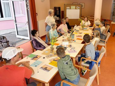 Mehrere Kinder und Erwachsene sitzen um einen Tisch.