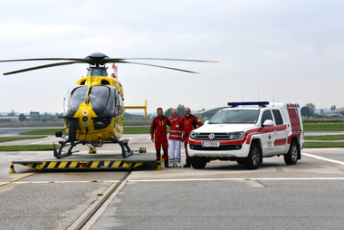 Leopold Hartl, Martin Wolschlager und Dr. Christian Kupplinger stehen zwischen dem Notarzthubschrauber C10 und dem Notarzteinsatzfahrzeug